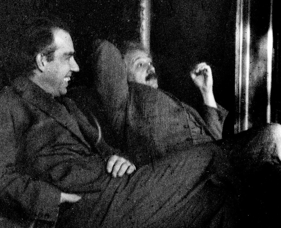 Einstein and Niels Bohr sit side-by-side, both relaxing and Bohr smiles.