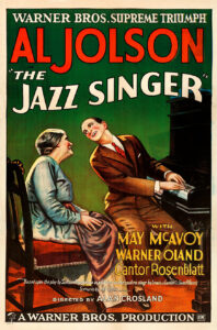 A colored poster of a man to the right of the posted in a brown suit, playing the piano while singing to his mother, who is to the left of the poster. She is wearing a light blue dress.