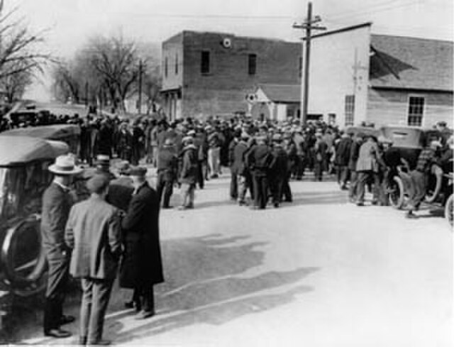 A black and white photo featuring hundreds of people waiting outside a doctor's office in the former mining town of Serene, Colorado. The photo was taken in 1927.