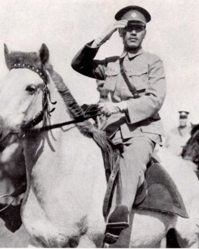 A man in military attire salutes from atop a horse.